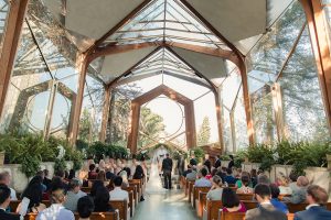 Summer outdoor wedding at south coast botanic gardens bride mermaid style gown with lace detail and sweetheart neckline with crystal belt and groom black suit with matching vest with white dress shirt and black bow tie with white floral boutonniere standing during ceremony