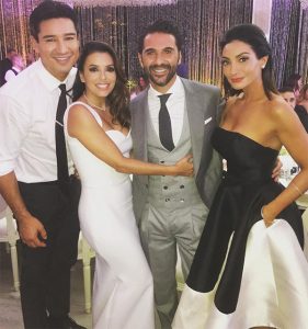 Celebrity wedding in mexico eva longoria mermaid style gown with straps and groom grey suit with white dress shirt and long black tie with matching vest standing with friends