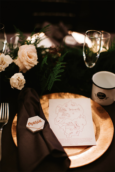 Orange county wedding at the estate on second dark brown wood table with gold place settings and white and green flower centerpiece decor with white glasses and candles