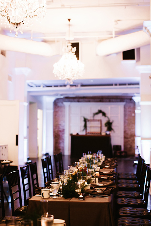 Orange county wedding at the estate on second dark brown wood table with gold place settings and white and green flower centerpiece decor with white glasses and candles and black chairs