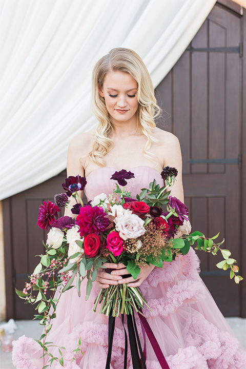 Los angeles valentine theme wedding shoot at the gardens at los robles bride pink ballgown dress with ruffled skirt and dark pink and white floral bridal bouquet close up