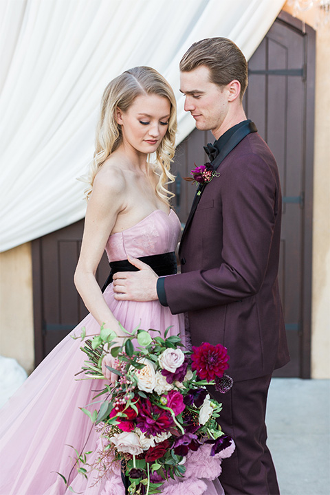 Los angeles valentine theme wedding shoot at the gardens at los robles bride pink ballgown dress with ruffled skirt and dark pink and white floral bridal bouquet with groom burgundy tuxedo with black dress shirt and black bow tie with red floral boutonniere