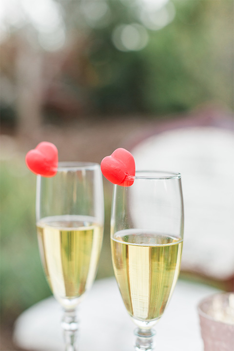 Los angeles valentine theme wedding shoot at the gardens at los robles vintage red and white lounge furniture with table and flower deocr and white and gold place settings with gold silverware with champagne glasses and heart decor
