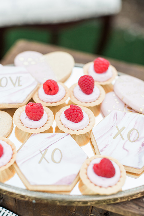 Los angeles valentine theme wedding shoot at the gardens at los robles vintage red and white lounge furniture with table and flower deocr and white and gold place settings with gold silverware and cookies with fruit and xo design