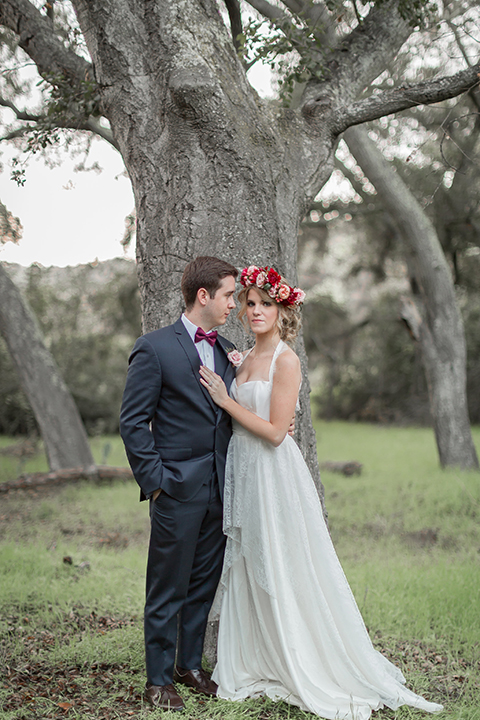 Valentine styled wedding shoot bride chiffon gown with halter straps and sweetheart neckline with groom navy blue suit with notch lapel with matching vest and white dress shirt with red bow tie and white floral boutonniere hugging
