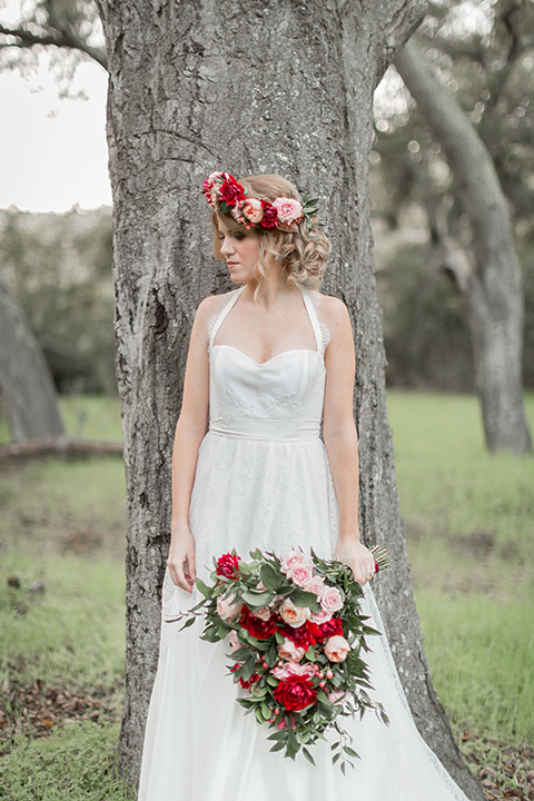 Valentine styled wedding shoot bride chiffon gown with halter straps and sweetheart neckline holding red and pink floral bridal bouquet with red flower crown