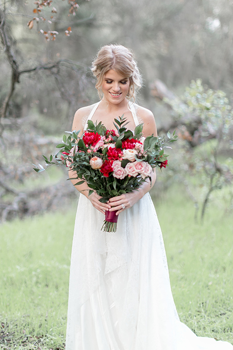 Valentine styled wedding shoot bride chiffon gown with halter straps and sweetheart neckline holding red and pink floral bridal bouquet