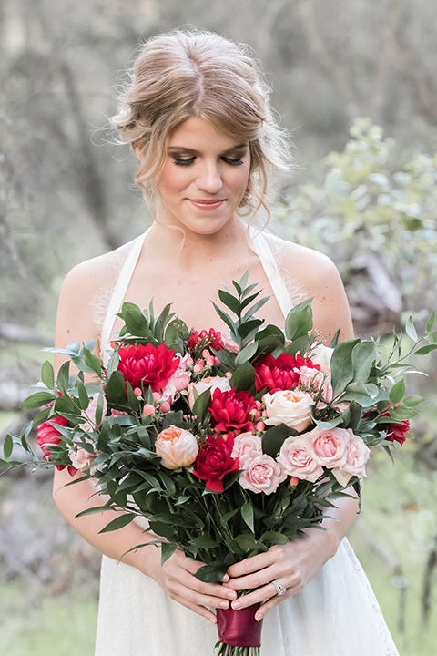 Valentine styled wedding shoot bride chiffon gown with halter straps and sweetheart neckline holding red and pink floral bridal bouquet with red flower crown