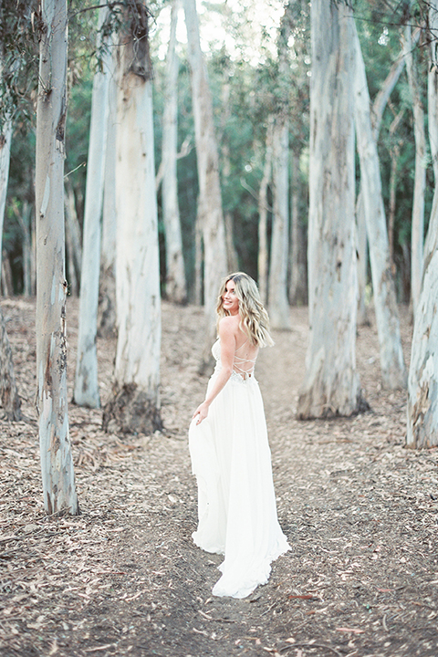 Into the woods outdoor romantic wedding shoot bride chiffon gown with thin spahetti straps and strap design on back with lace detail and sweetheart neckline holding dress