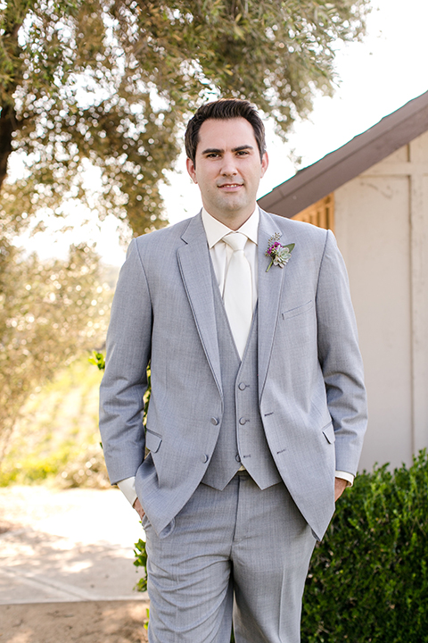 Temecula outddor wedding at callaway winery groom heather grey suit with matching vest and white dress shirt with long ivory tie and purple floral boutonniere