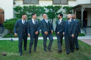 Long beach burgundy wedding at the loft on pine groom charcoal grey tuxedo with black shawl lapel and matching vest with white dress shirt and long plaid tie with groomsmen charcoal grey suits with matching vests and white dress shirts with long plaid ties and white floral boutonnieres