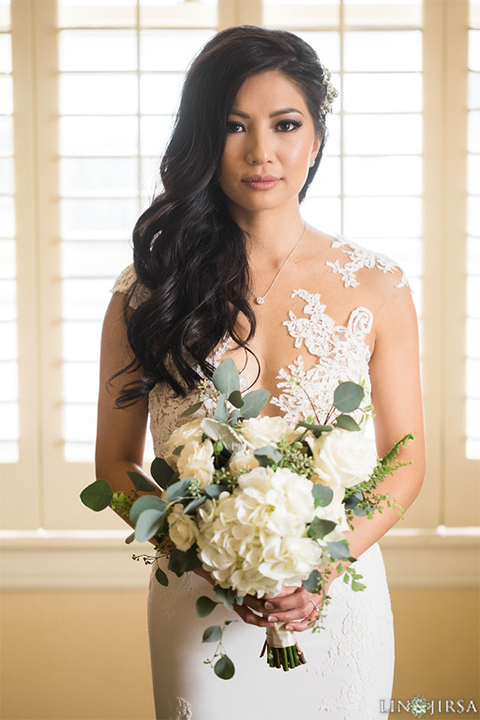 Downtown los angeles wedding bride form fitting lace gown with illusion back and high neckline with crystal hair piece wedding photo idea for bride holding white and green floral bridal bouquet