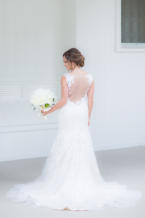 San diego wedding at the crossings carlsbad bride form fitting lace gown with thin straps and ruffled skirt with sweetheart neckline holding white floral bridal bouquet