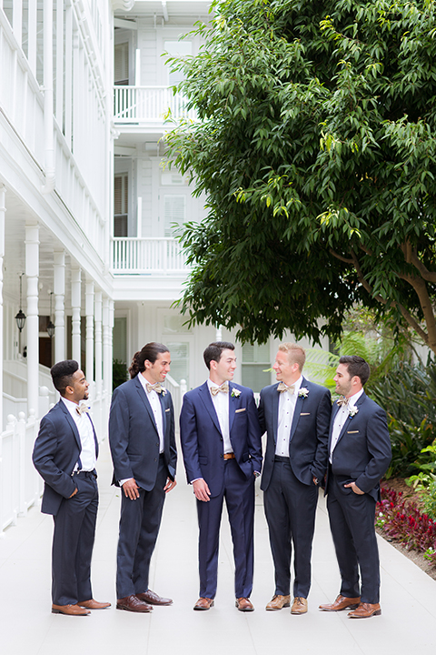 San diego wedding at the crossings carlsbad groom cobalt blue suit with white dress shirt and gold bow tie with matching pocket square and white floral boutonniere with groomsmen grey suits with white dress shirts and bow ties