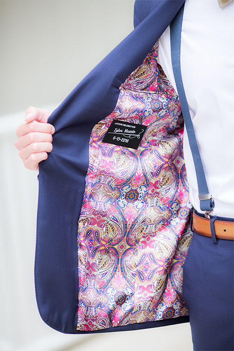San diego wedding at the crossings carlsbad groom cobalt blue suit with white dress shirt and gold bow tie with matching pocket square and white floral boutonniere with pink paisley design on inside of jacket with blue suspenders and brown belt