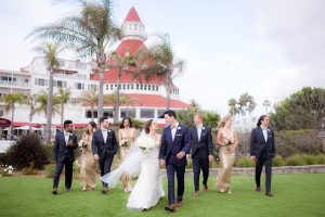 San diego wedding at the crossings carlsbad bride form fitting lace gown with thin straps and ruffled skirt with sweetheart neckline and long veil with groom cobalt blue suit with white dress shirt and gold bow tie with matching pocket square and white floral boutonniere with bridesmaids long gold sequined dresses with groomsmen grey suits with white dress shirts and bow ties walking