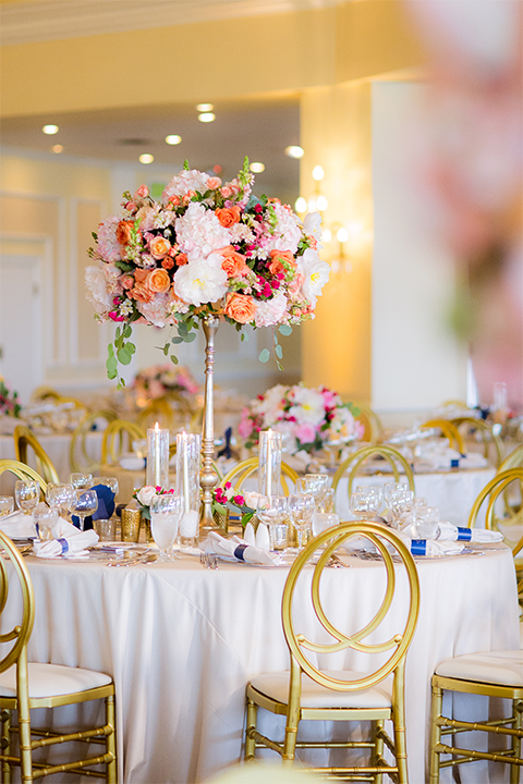 San diego wedding at the crossings carlsbad table set up with white table linen and gold chairs with white and pink flower centerpiece decor with white place settings and candle decor with blue and gold table numbers