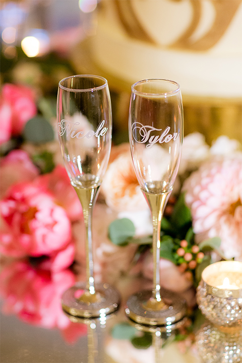 San diego wedding at the crossings carlsbad table set up with white table linen and gold chairs with white and pink flower centerpiece decor with white place settings and candle decor with blue and gold table numbers with bride and groom champagne flutes for toast