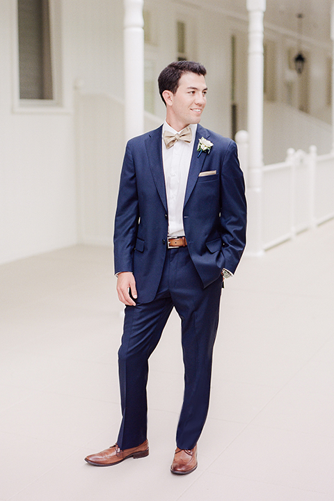 San diego wedding at the crossings carlsbad groom cobalt blue suit with white dress shirt and gold bow tie with matching pocket square and white floral boutonniere