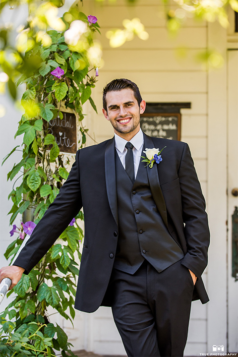 San diego wedding at green gables estate groom black shawl lapel tuxedo with matching vest and white dress shirt with long black skinny tie and white floral boutonniere