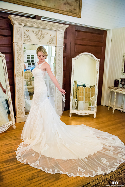 San diego wedding at green gables estate bride form fitting lace gown with a long train and high illusion neckline with long veil holding white and blue floral bridal bouquet