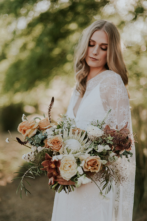 San diego outdoor wedding shoot at the san diego zoo and safari park bride white chiffon gown with lace sleeves and thin straps with plunging neckline holding white and orange floral bridal bouquet