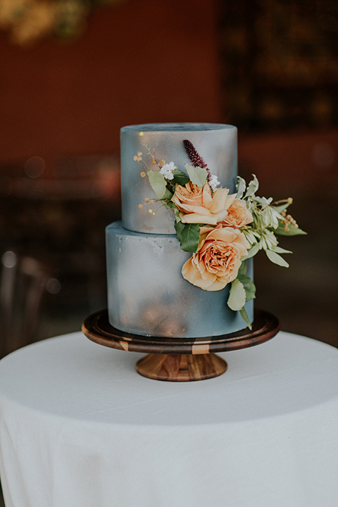 San diego outdoor wedding shoot at the zoo and safari park wedding cake two tier light blue wedding cake with light orange flower decor on side and brown cake stand with no cake topper on white table linen