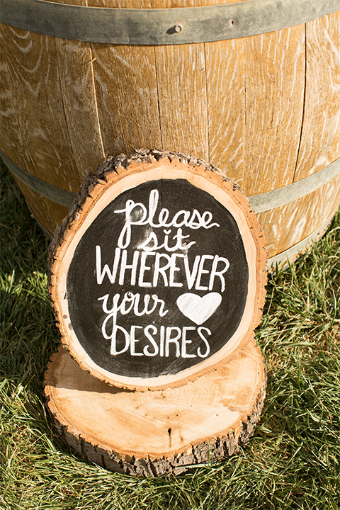Temecula outdoor rustic wedding at the lake oak meadows ceremony decor wine barrel with wood tree stump and black and white chalkboard design on the grass wedding photo idea for ceremony decor