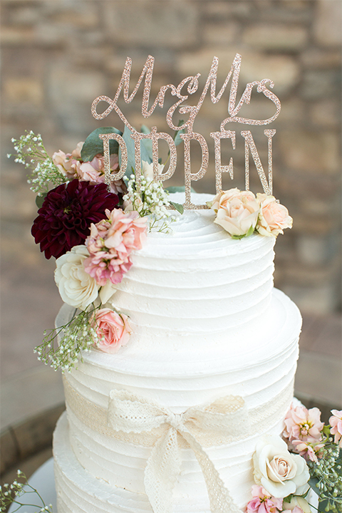 Temecula outdoor rustic wedding at the lake oak meadows wedding cake decor two tier white wedding cake with white and red flower decor on top and calligraphy cake topper wedding photo idea for cake