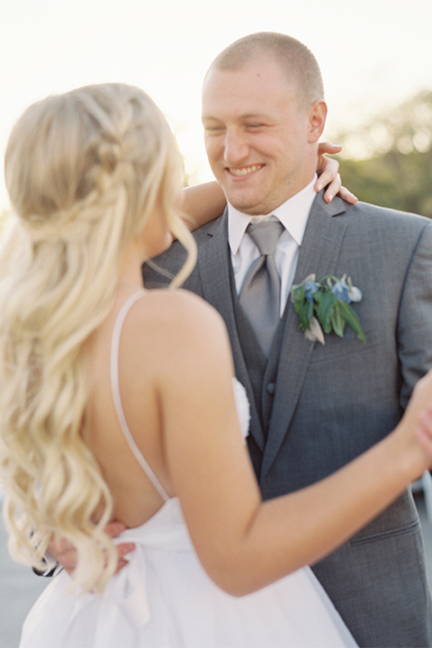 Southern california wedding at riverview free church bride strapless ball gown with a sweetheart neckline and tulle skirt with a long veil and braided hairstyle with groom grey notch lapel suit with matching vest and white dress shirt with long grey tie and light blue and green floral boutonniere holding hands and dancing