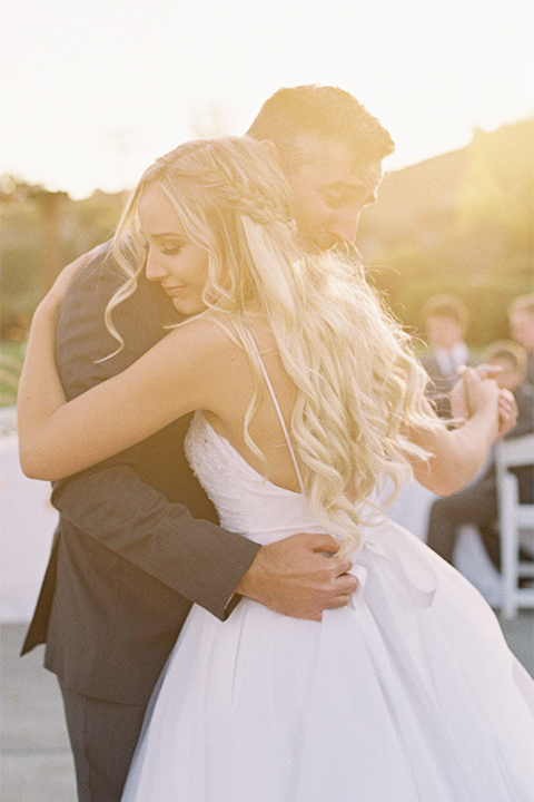 Southern california wedding at riverview free church bride strapless ball gown with a sweetheart neckline and tulle skirt with a long veil and braided hairstyle with groom grey notch lapel suit with matching vest and white dress shirt with long grey tie and light blue and green floral boutonniere hugging and dancing