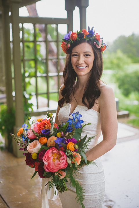 Temecula outdoor wedding at temecula creek inn bride form fitting simple strapless gown with a straight neckline and teal rain boots wearing colorful floral crown holding colorful floral bridal bouquet
