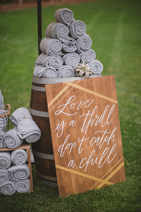 Temecula outdoor wedding at temecula creek inn ceremony set up with decor wooden sign with white calligraphy writing and towel for rain on wine barrel wedding photo idea for ceremony decor