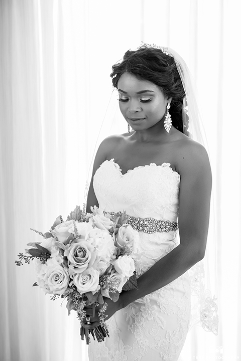 San diego outdoor wedding at ultimate skybox bride form fitting strapless lace gown with a sweetheart neckline and crystal belt with long veil holding white floral bridal bouquet black and white