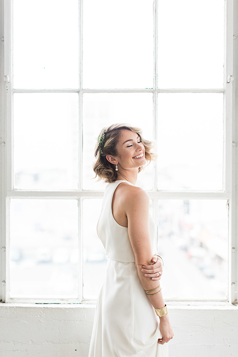 Downtown los angeles wedding shoot at fd photo studio bride form fitting simple gown with a high halter neckline holding white and green floral bridal bouquet