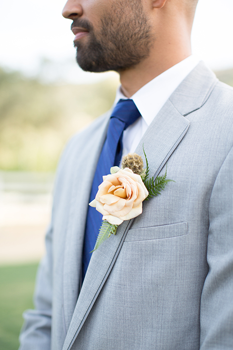 Los angeles outdoor wedding at brookview ranch groom heather grey notch lapel suit with a matching vest and white dress shirt and long blue tie and white floral boutonniere standing close up